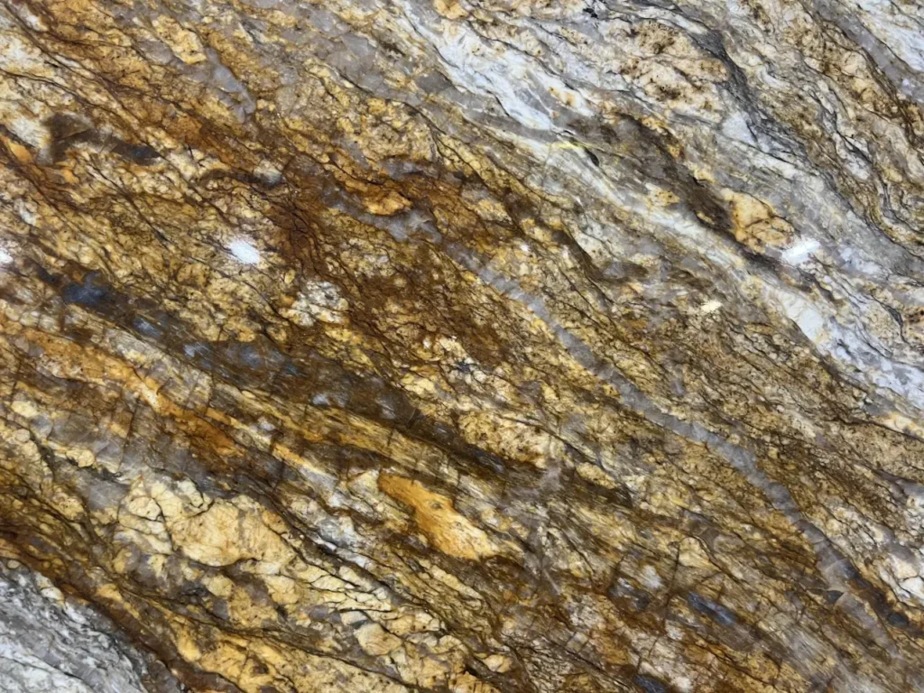 Close-up of a Fusion Gold granite slab featuring dramatic gold, brown, gray, and cream flowing patterns for luxury countertops in Knoxville, Tennessee.