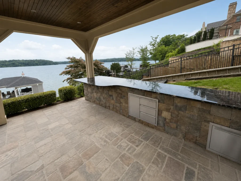 Covered outdoor kitchen with granite countertops in East Tennessee overlooking a lake and landscaped backyard.
