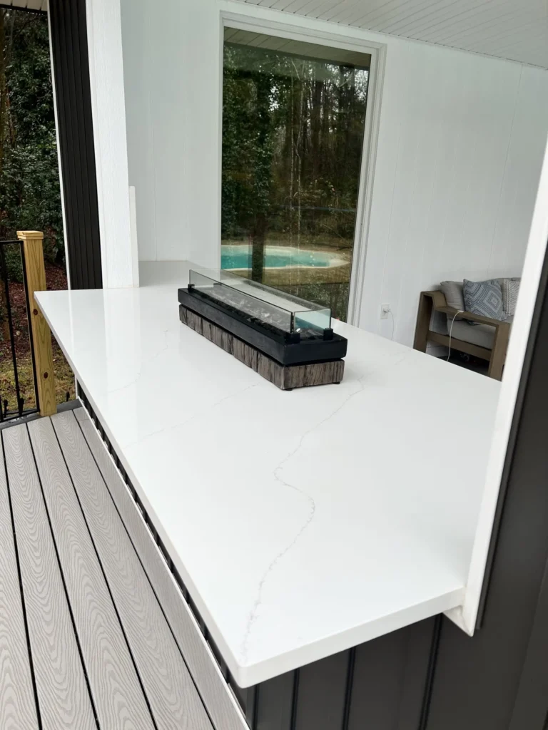 White Calacatta-style quartz outdoor bar countertop with subtle gray veining on a covered patio overlooking a backyard pool in Knoxville, Tennessee.