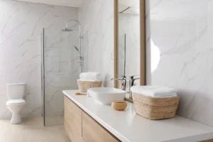 Modern bathroom featuring white quartz vanity countertops, vessel sink, light wood floating vanity, frameless glass shower, and marble-look wall panels in Knoxville, Tennessee.