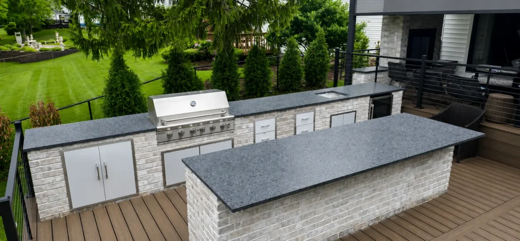 Steel Grey leathered granite countertops on a custom outdoor kitchen with stainless steel grill, bar island, and built-in storage in Knoxville, Tennessee.