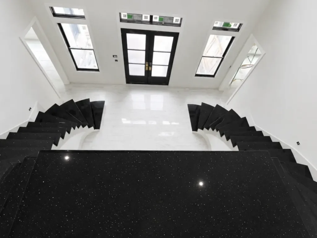 Grand entryway with black quartz stair treads in East Tennessee featuring a dual curved staircase and modern design.