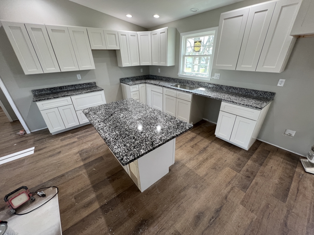 Luna Pearl granite countertops and kitchen island installed with white shaker cabinets.